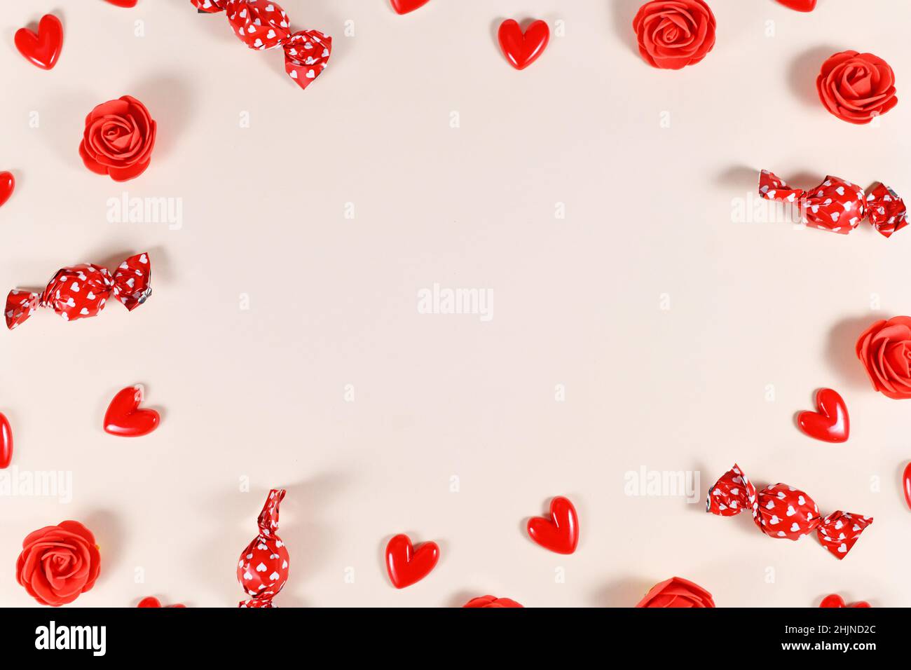 Saint-Valentin bonbon, confettis en forme de coeur et roses rouges formant un cadre autour de beige avec l'espace de copie Banque D'Images