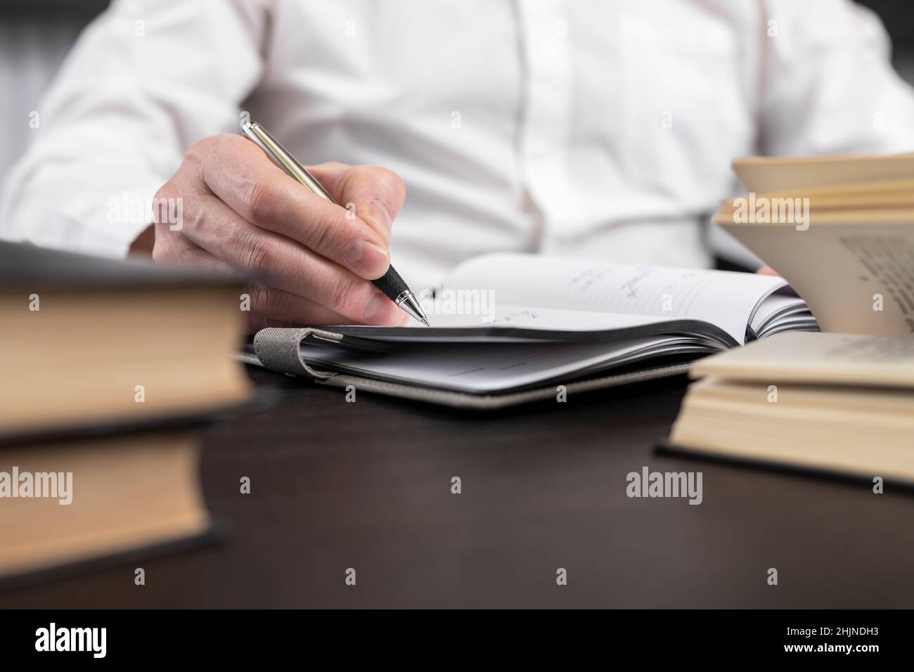 Homme mains prendre des notes dans le planificateur.Homme assis à un bureau à la maison ou au bureau et étudiant, recherchant et analysant des informations dans des livres ou des codes.Concept d'apprentissage et d'éducation aux entreprises.Photo Banque D'Images
