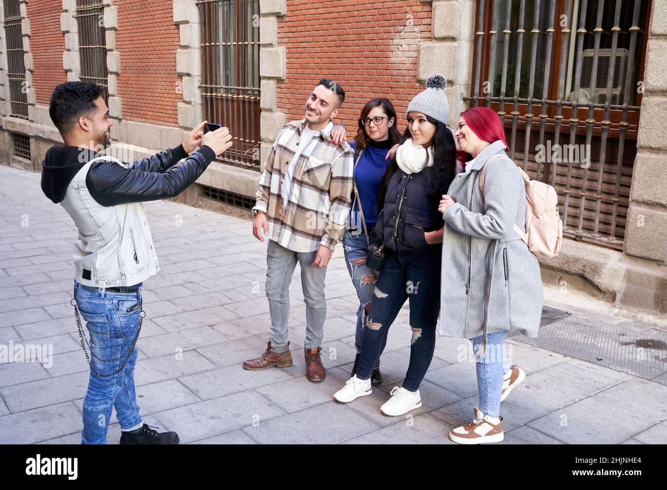 Latino homme prenant une photo avec son smartphone de son groupe d'amis dans une rue de ville. Banque D'Images