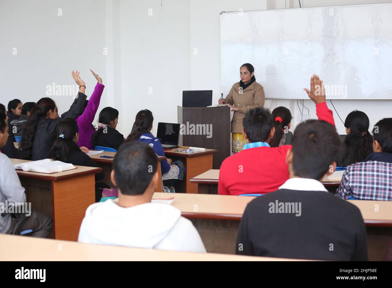 Jeunes étudiants levant la main dans une salle de classe montrant qu'ils sont prêts - étudiants dans la classe d'université en Inde Banque D'Images