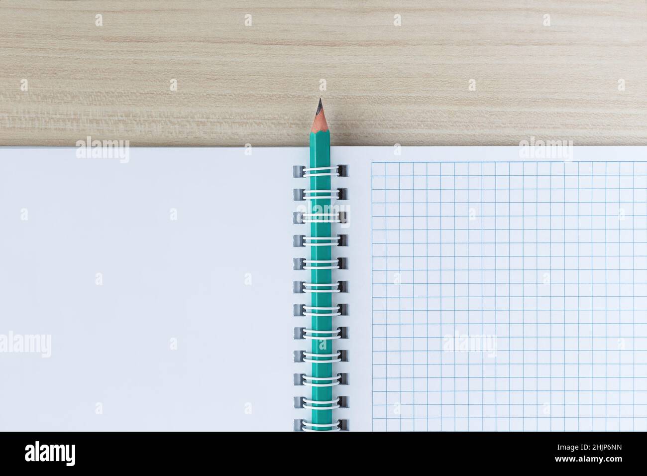 Un crayon inséré dans un clip en spirale d'un bloc-notes, sur une table en bois.Vue de dessus Banque D'Images