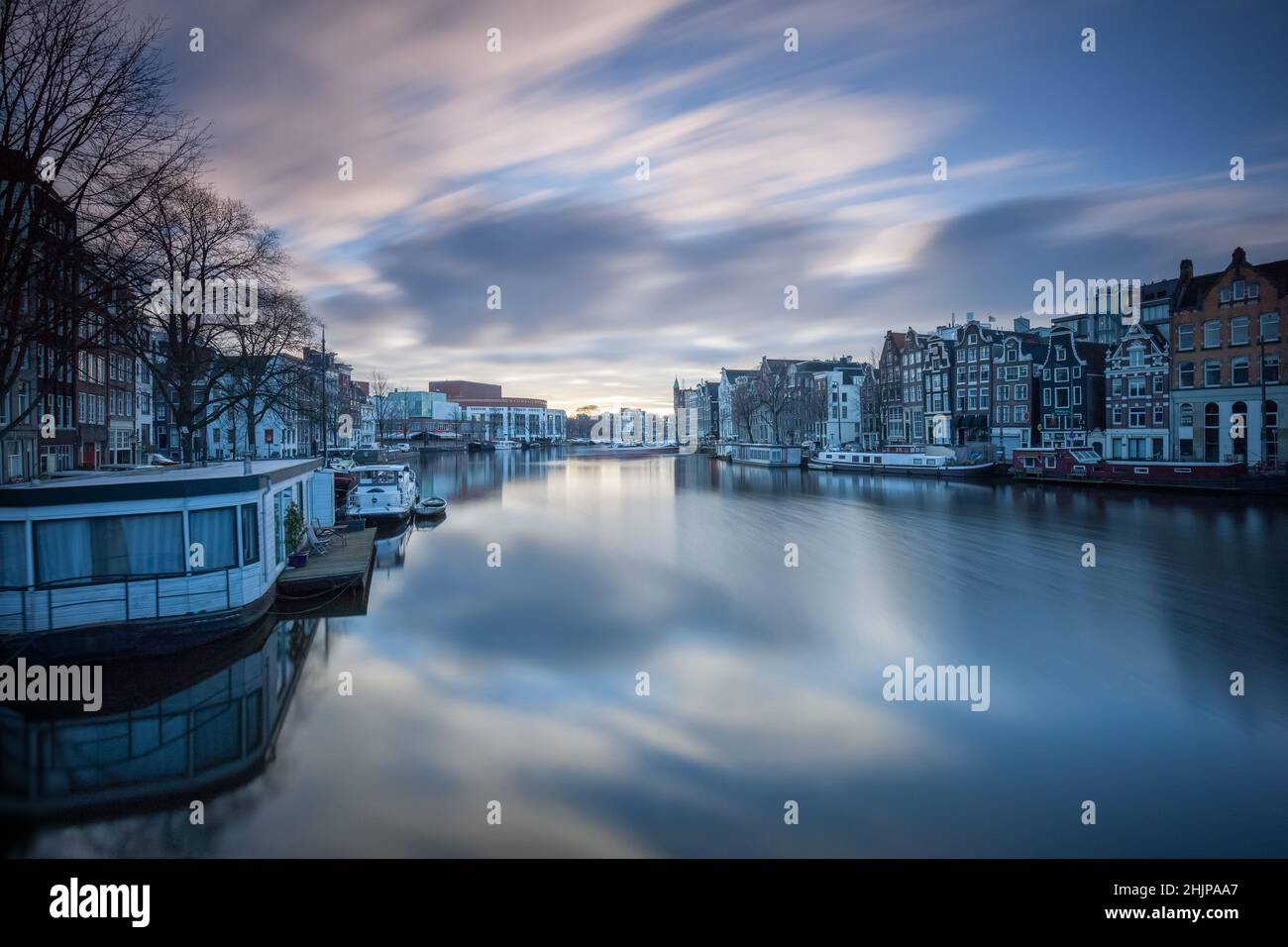 Vue sur le canal d'Amsterdam au lever du soleil avec une longue exposition, des bateaux-maisons et des barges fluviales amarrées Amsterdam, Hollande Banque D'Images