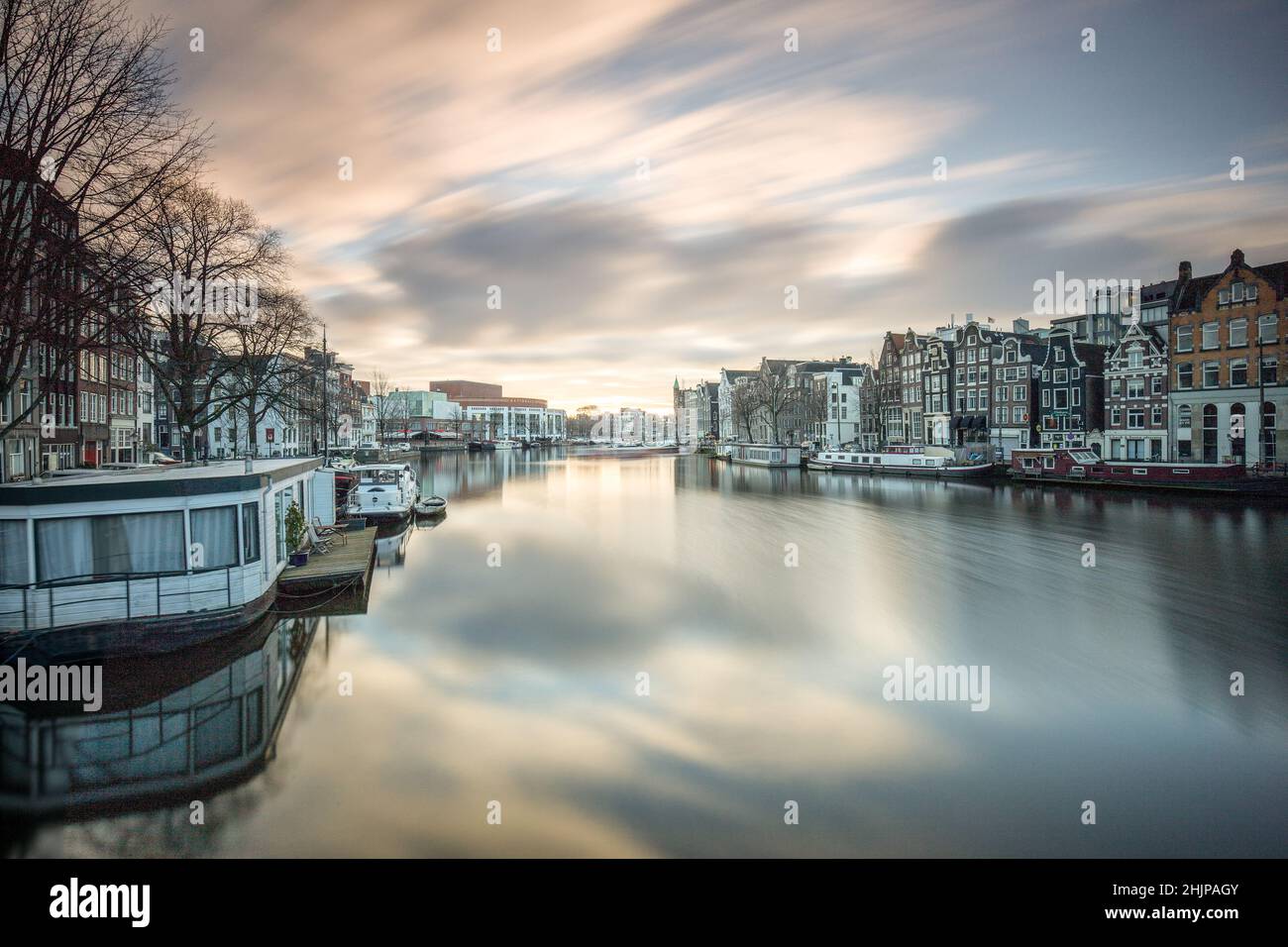 Vue sur le canal d'Amsterdam au lever du soleil avec une longue exposition, des bateaux-maisons et des barges fluviales amarrées Amsterdam, Hollande Banque D'Images