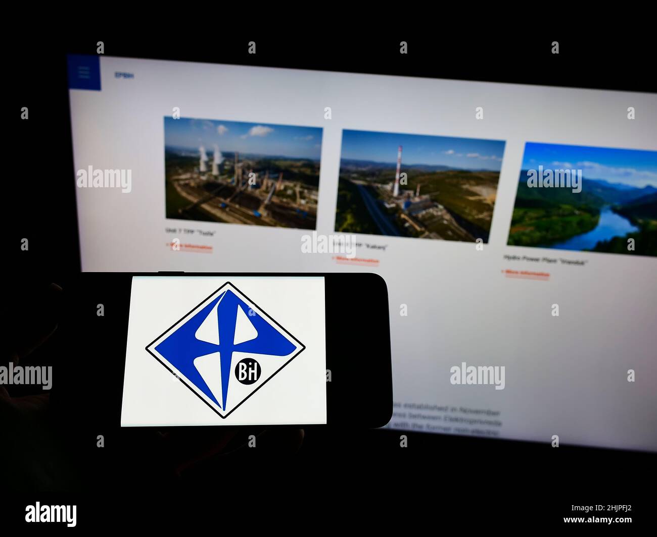 Personne tenant un téléphone portable avec le logo de la société de services publics bosniaque Elektroprivreda BiH à l'écran en face de la page Web d'affaires.Mise au point sur l'affichage du téléphone. Banque D'Images
