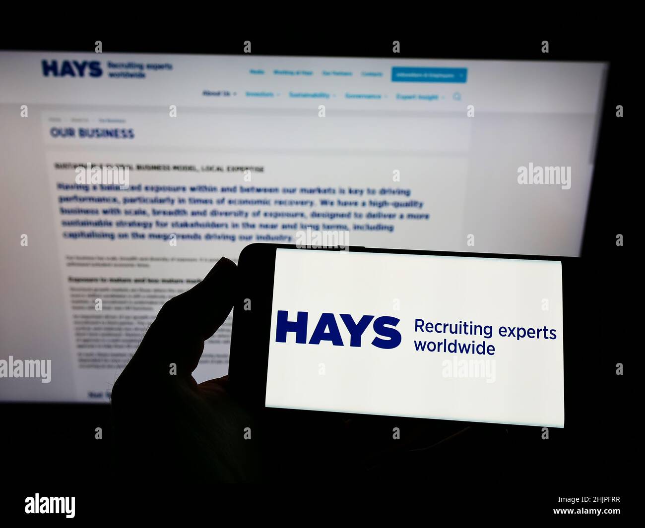 Personne tenant un smartphone avec le logo de la société de recrutement britannique Hays plc à l'écran devant le site Web.Mise au point sur l'affichage du téléphone. Banque D'Images