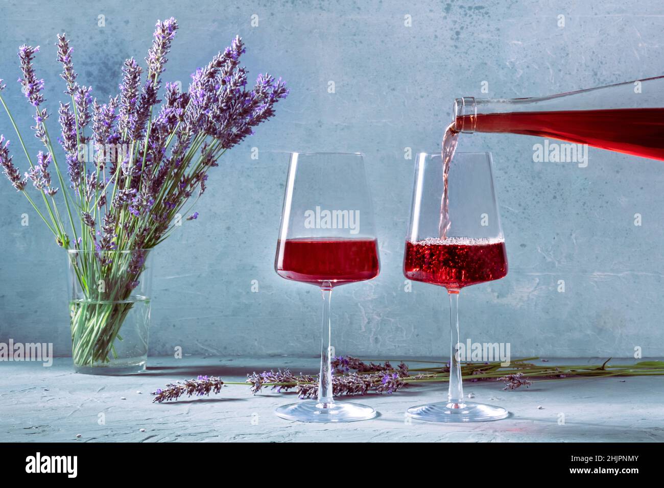 Vin versé dans des verres d'une bouteille, avec des fleurs de lavande en arrière-plan.Une dégustation de vins de Provence Banque D'Images