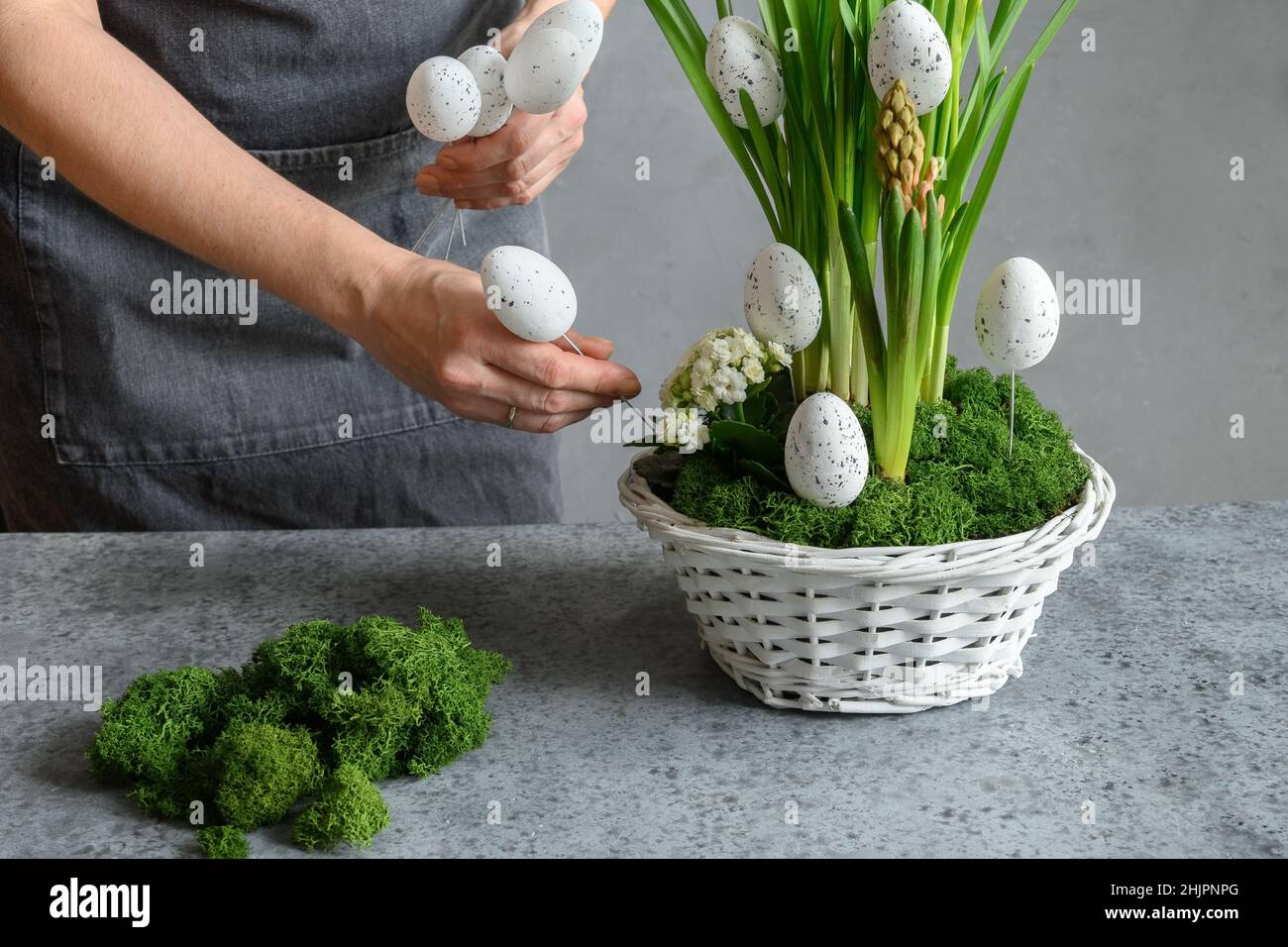 Composition de Pâques à motif floral pour table centrale avec œufs blancs, mousse et lapin.Gros plan.Femme faire décor de printemps. Banque D'Images