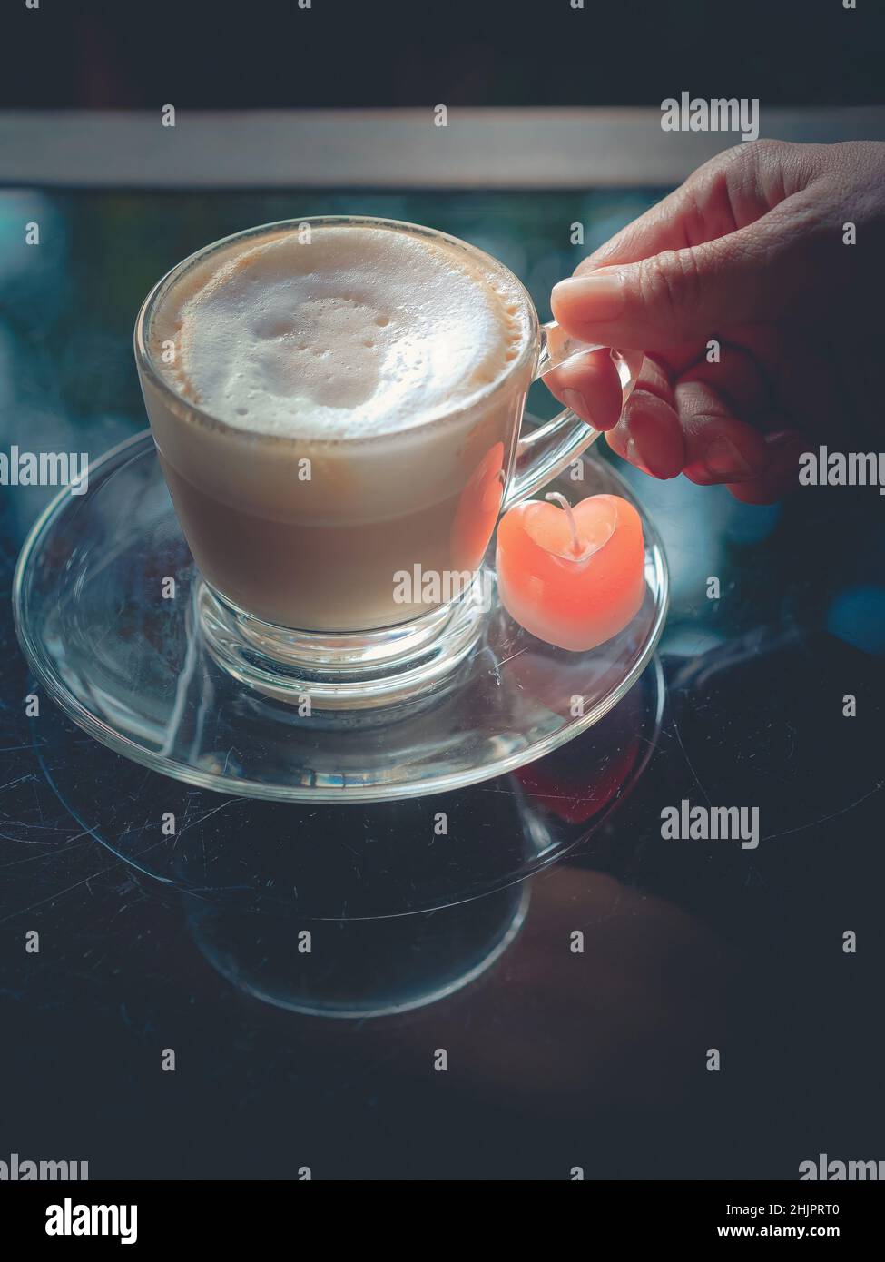 Main d'une femme tenant une tasse de cappuccino chaud avec une bougie en  forme de coeur rouge sur des dessous de verre rayés table.Vintage, rétro,  style ancien.Image Photo Stock - Alamy