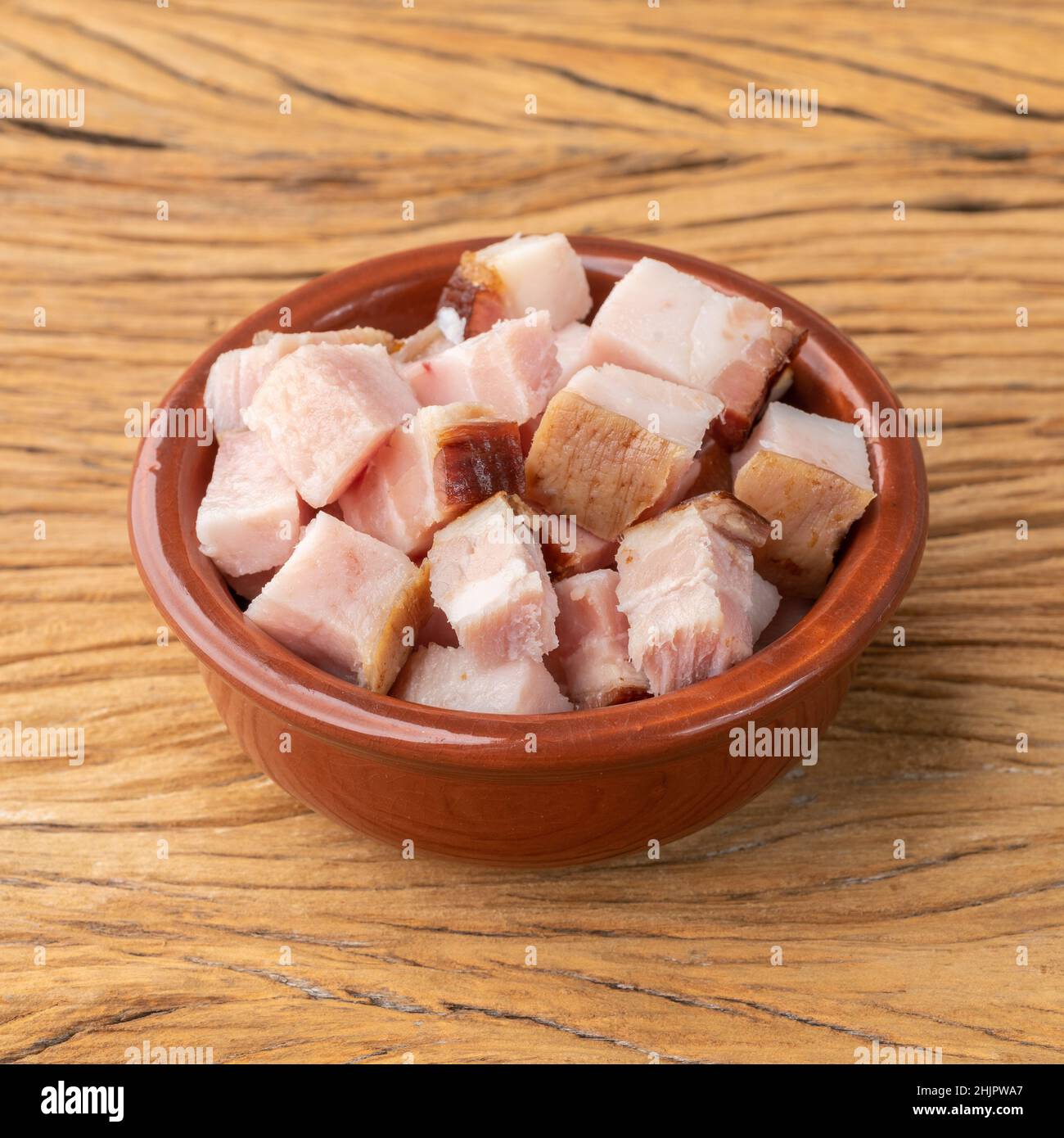 Cubes de bacon fumé dans un bol sur planche de bois. Banque D'Images