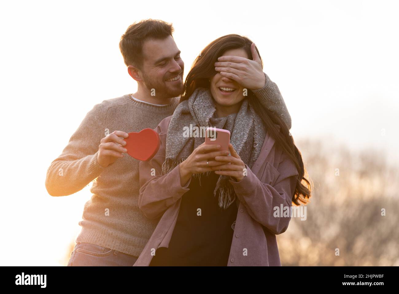 Jeune couple célébrant la Saint-Valentin en donnant un cadeau sur un parc Banque D'Images