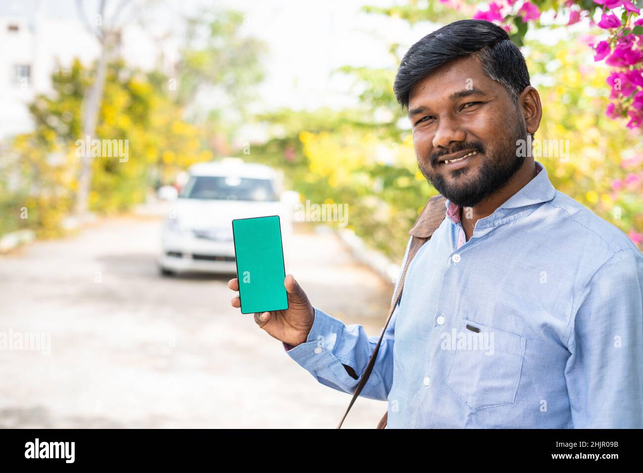 Souriant jeune passager montrant le téléphone mobile à écran vert en regardant la caméra - concept de taxi en ligne ou service de réservation de taxi, publicité d'application et Banque D'Images