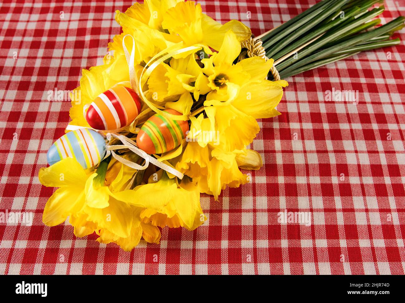 Carte de Pâques festive. Bouquet de Pâques de jonquilles jaunes et d'œufs peints à la main sur une table à carreaux. Place pour votre texte. Bouq. De printemps Banque D'Images