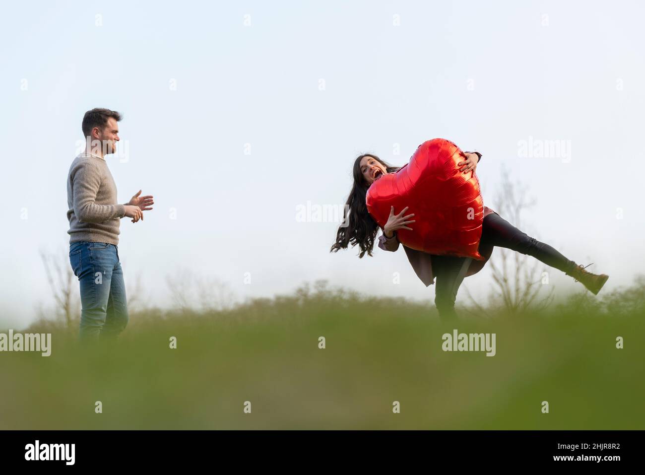 Jeune couple célébrant le jour de la Saint-Valentin jouant avec un ballon en forme de cœur Banque D'Images