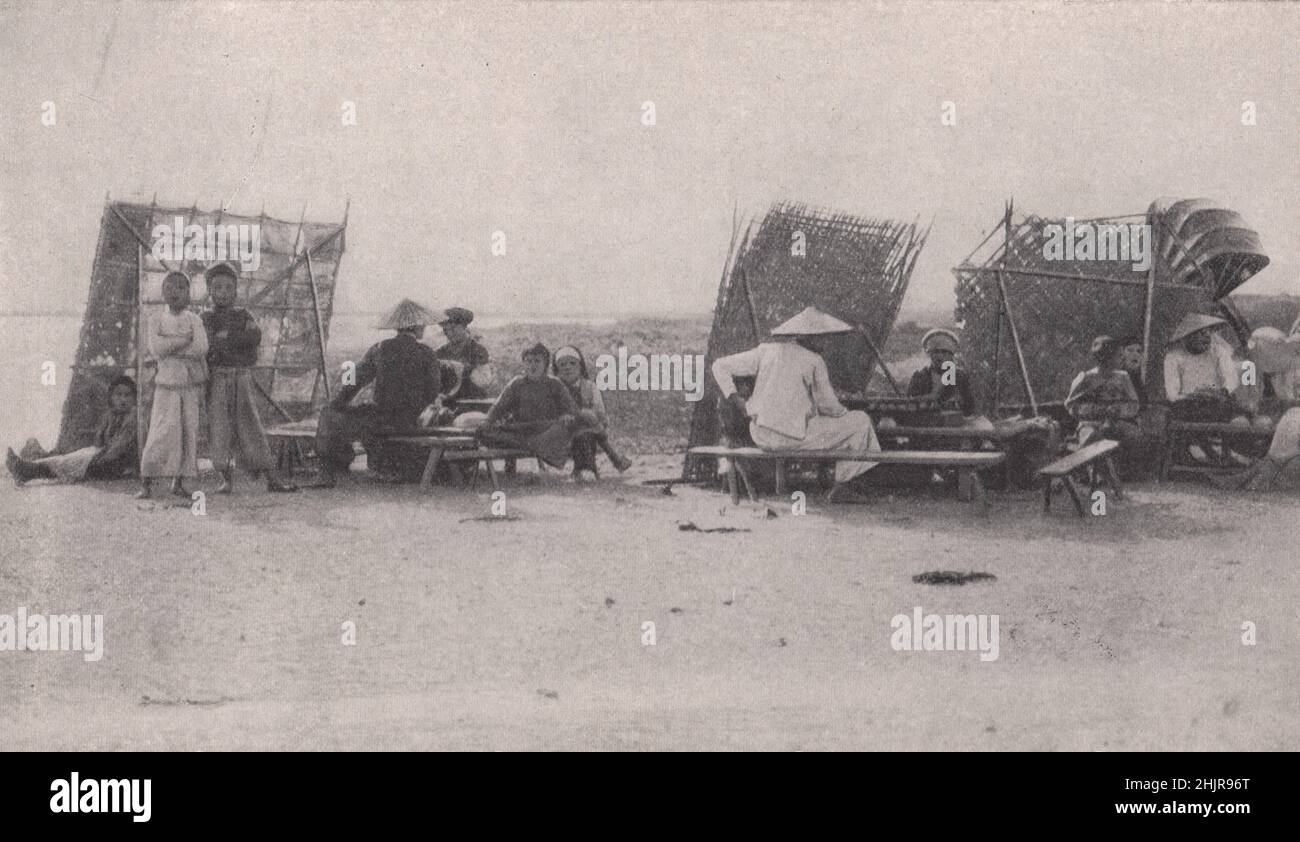 Les vendeurs du marché à leurs stands avec des écrans de tapis à côté de la voie à Haiphong. Vietnam (1923) Banque D'Images