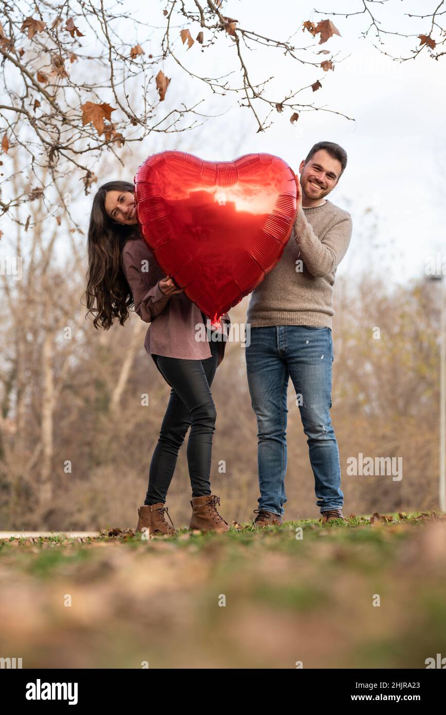 Jeune couple célébrant la Saint-Valentin en tenant une montgolfière en forme de cœur Banque D'Images