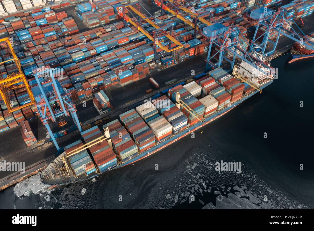 Vladivostok, Russie - 26 janvier 2022 : Vue de dessus du terminal des conteneurs du port maritime.En hiver, un bateau à conteneurs est en train de charger à l'embarcadère. Banque D'Images