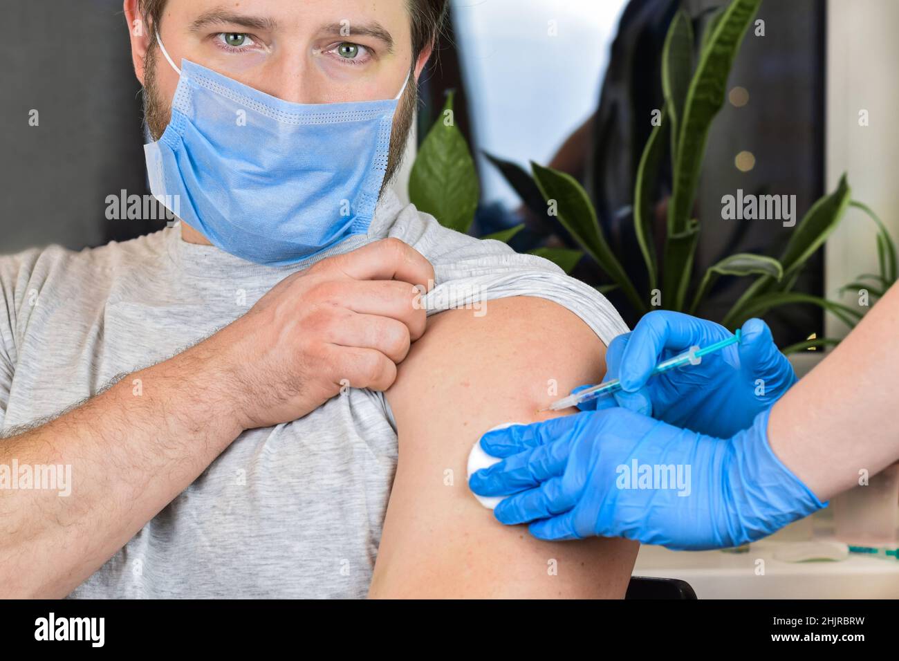 Mains du médecin injectant le vaccin contre le coronavirus covid-19 dans une seringue de vaccin dans le muscle du bras de l'homme caucasien pour l'immunisation contre le covid. Banque D'Images