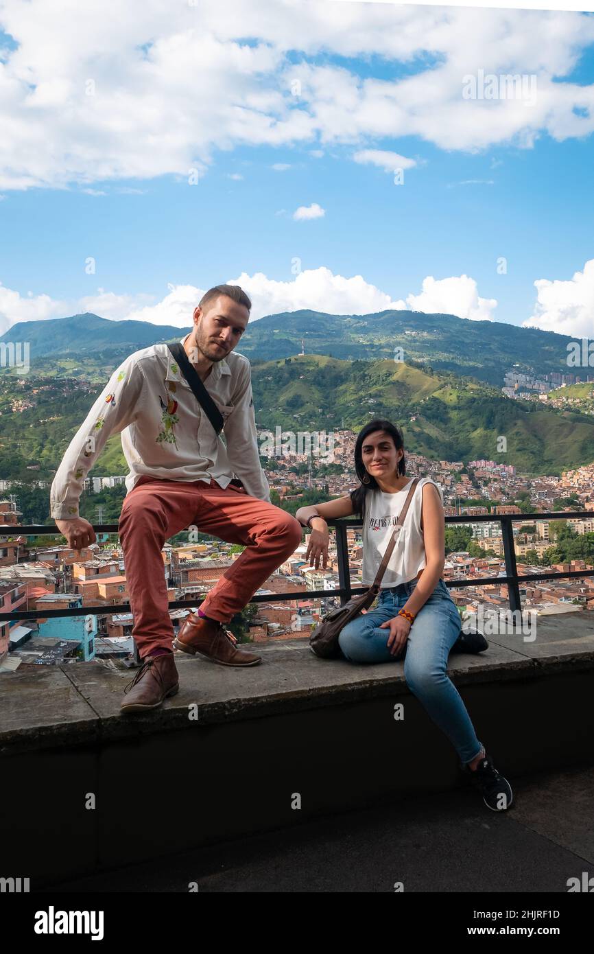 L'homme blanc et la femme à cheveux noirs rient et regardent la caméra avec le fond de la ville de Medellin, Colombie Banque D'Images