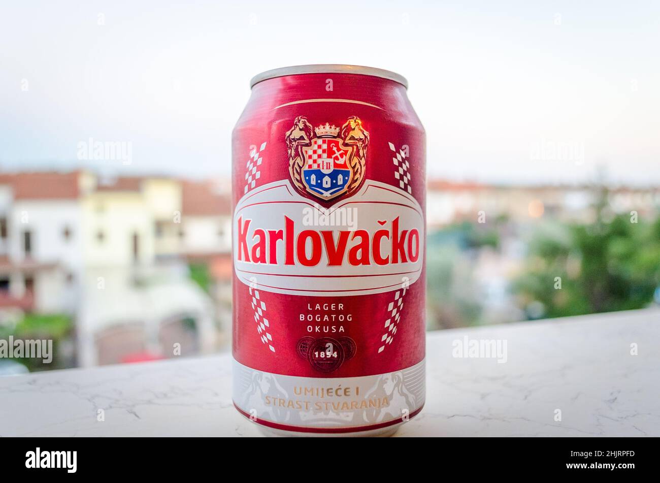 CAN rouge isolé de la bière populaire croate Karlovacko. Bâtiments Pula en arrière-plan flou. Fabriqué à la brasserie Karlovac, Croatie. Banque D'Images