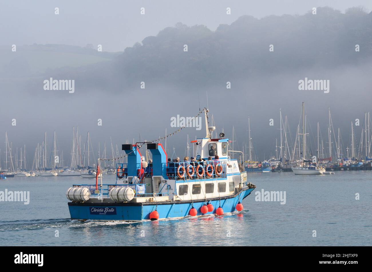 Les gens à bord d'un ferry pour passagers sur la rivière Dart, un matin calme et brumeux, le soleil commence à se briser dans la brume.Dartmouth, Devon, Angleterre, Royaume-Uni Banque D'Images