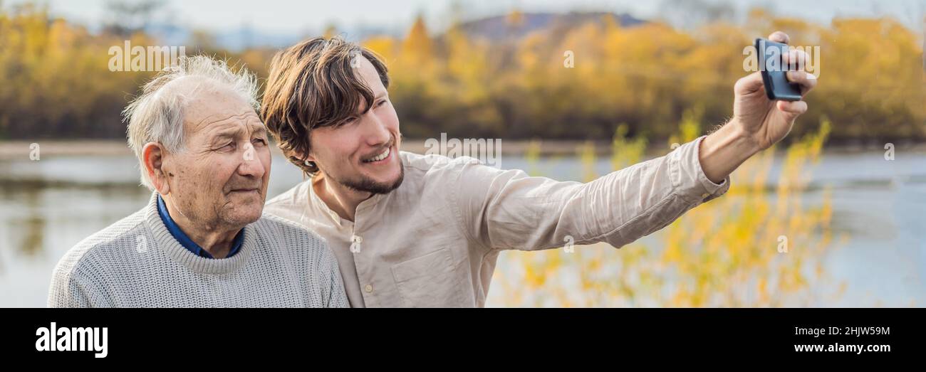 Un homme prend un selfie avec une bannière d'homme plus ancien, FORMAT LONG Banque D'Images