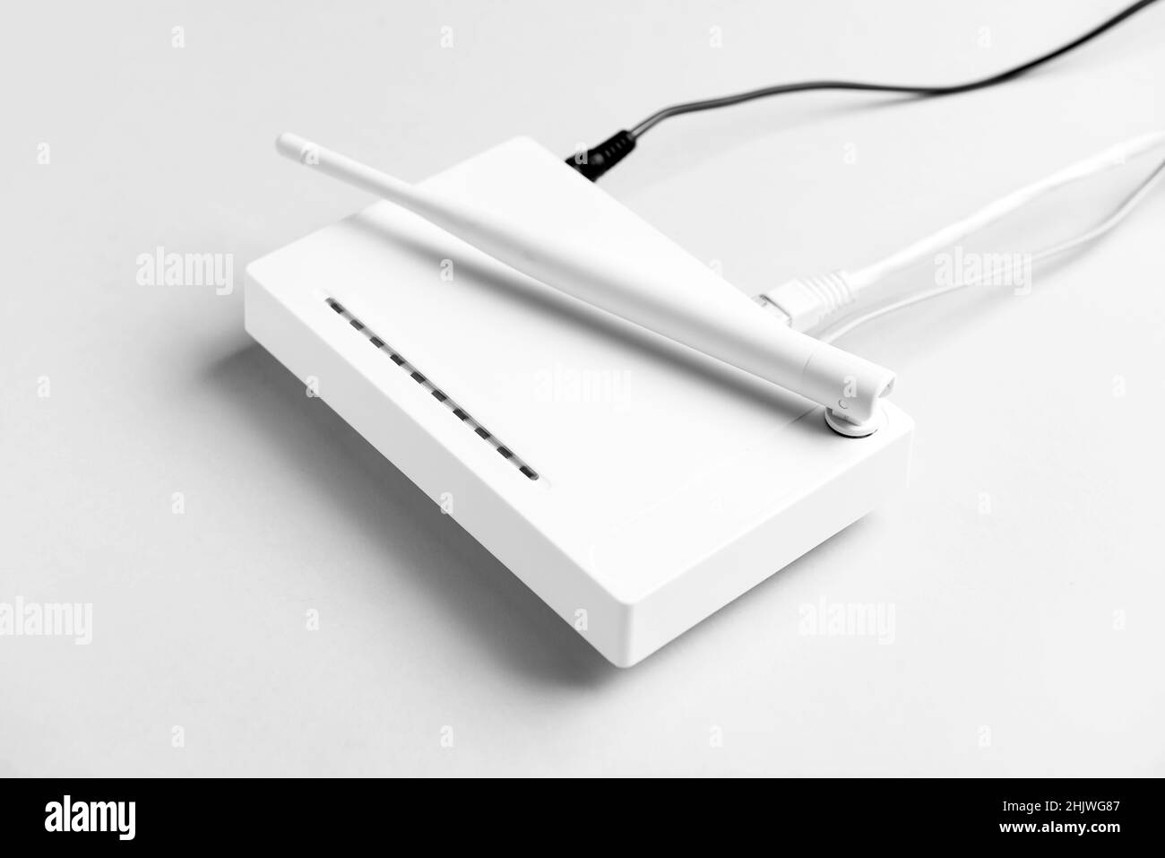 Routeur Wi-Fi avec antenne et câbles réseau sur fond clair Banque D'Images