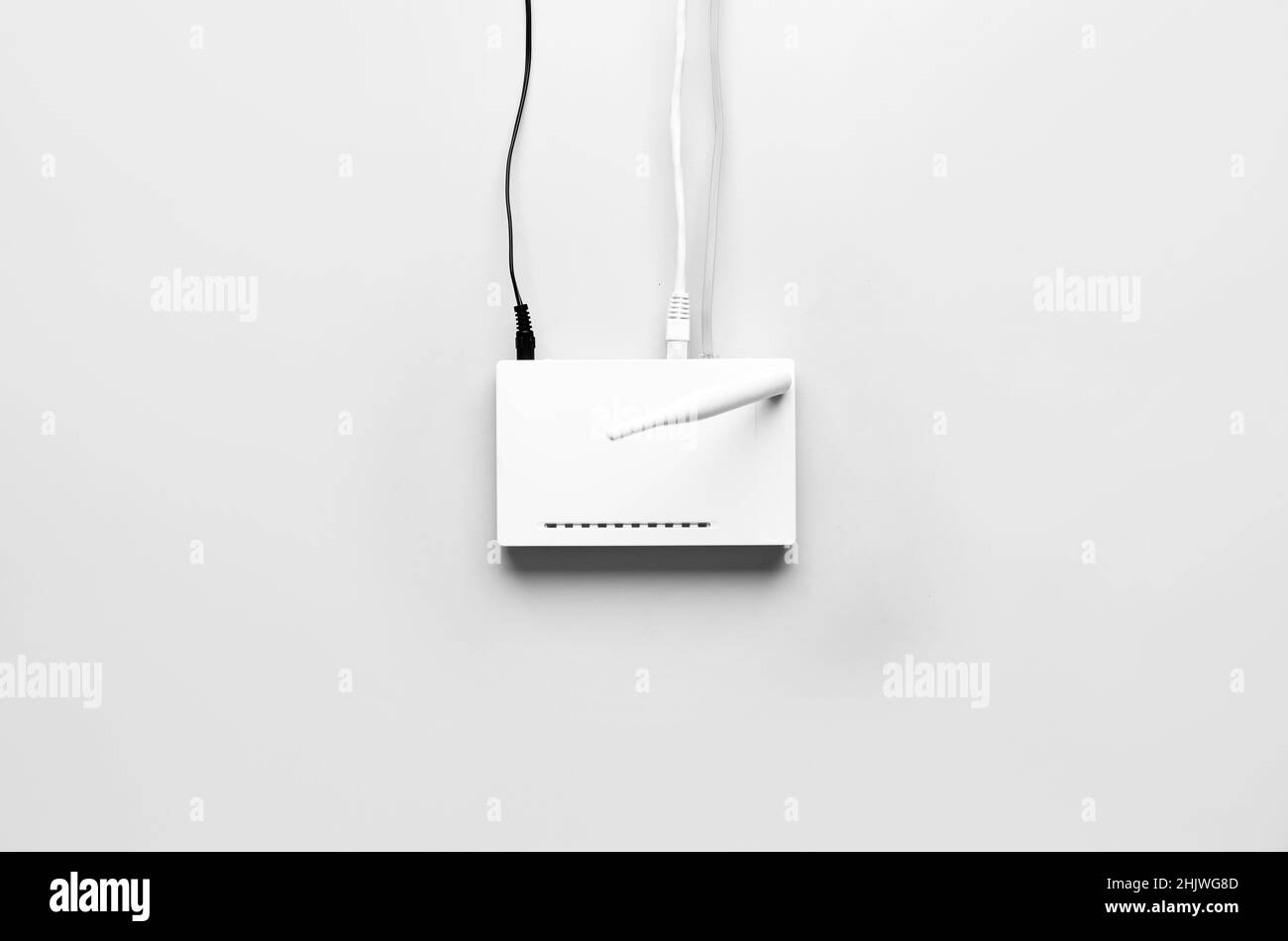 Routeur Wi-Fi avec antenne et câbles réseau sur fond clair Banque D'Images