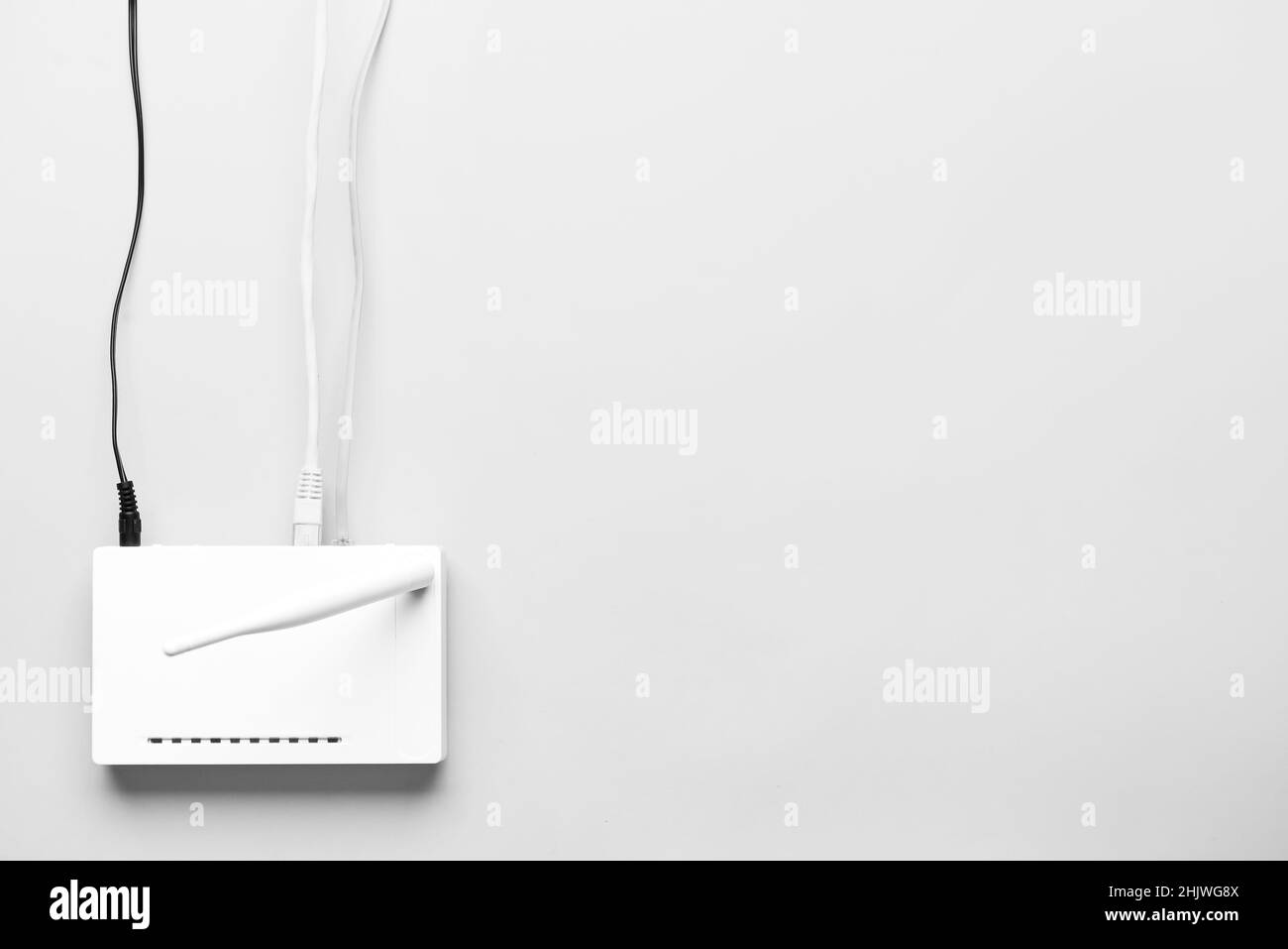 Routeur Wi-Fi avec antenne et câbles réseau sur fond clair Banque D'Images