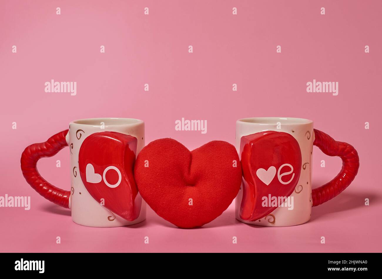 Deux mugs appariés avec l'inscription Love et un coeur rouge en peluche entre eux Banque D'Images
