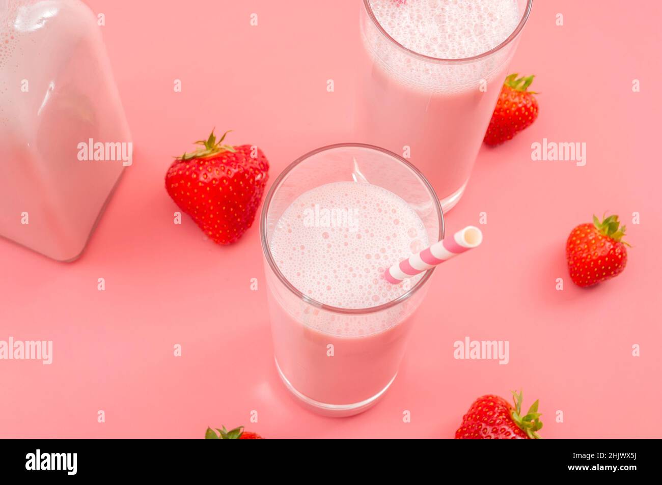 Desserts rafraîchissants d'été et boisson saine riche en calcium thème avec verres de lait de fraise, bouteille de verre, pailles rayées et St épars Banque D'Images
