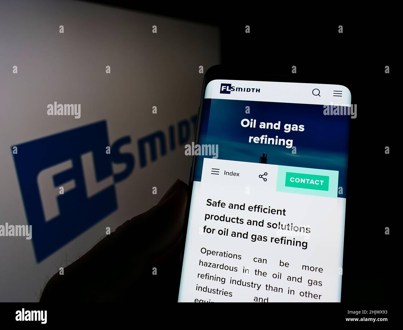 Personne tenant un téléphone portable avec la page web de l'ingénierie danoise FLSMIDth Co. COMME à l'écran devant le logo de l'entreprise.Mise au point sur l'affichage du téléphone. Banque D'Images