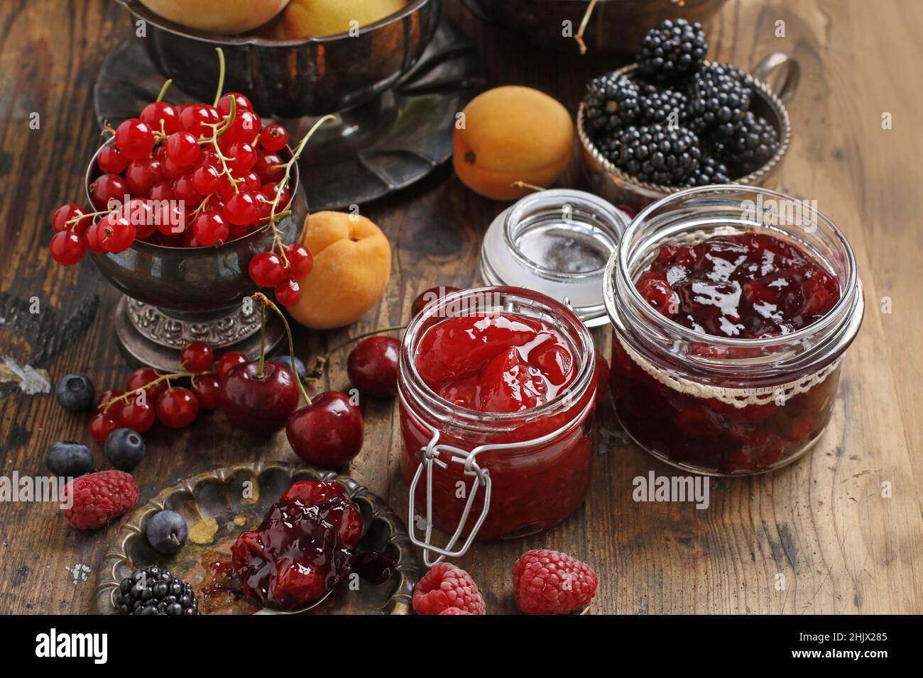Pots de confiture de fraises de cerise parmi les fruits d'été et d'automne sur une table en bois. Banque D'Images
