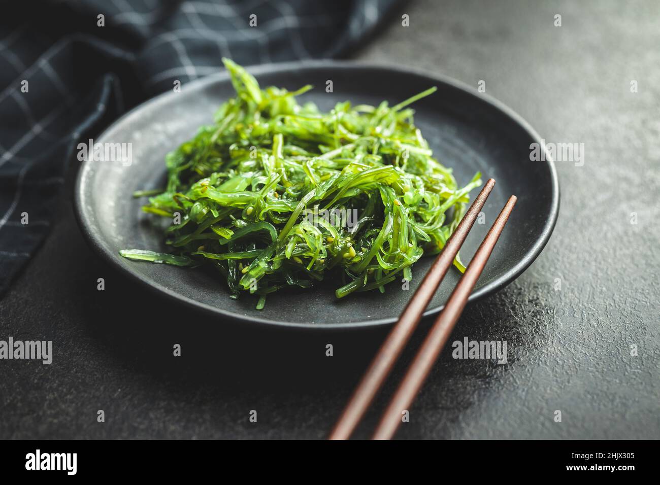 Wakame vert.Salade d'algues sur assiette noire. Banque D'Images