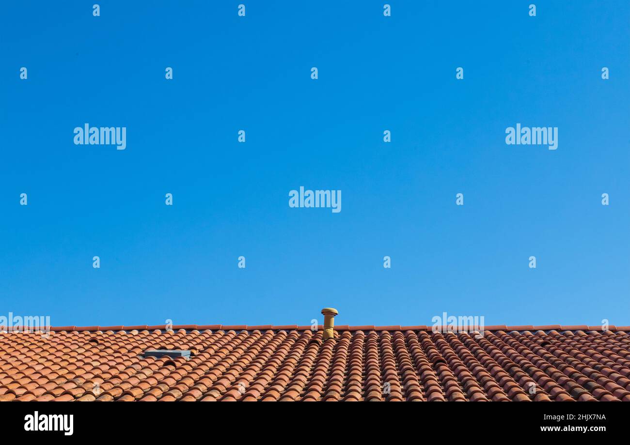 Sur fond de ciel bleu clair, un toit orange contrasté fait de vieux carreaux Banque D'Images