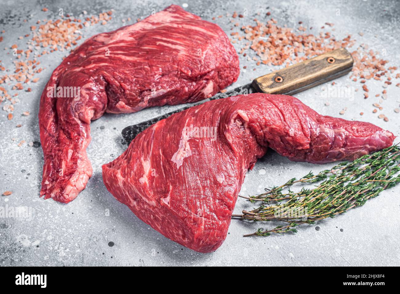Steak de sirloin à trois pointes non coké sur une table à mousseur avec un plat à viande.Arrière-plan gris.Vue de dessus Banque D'Images