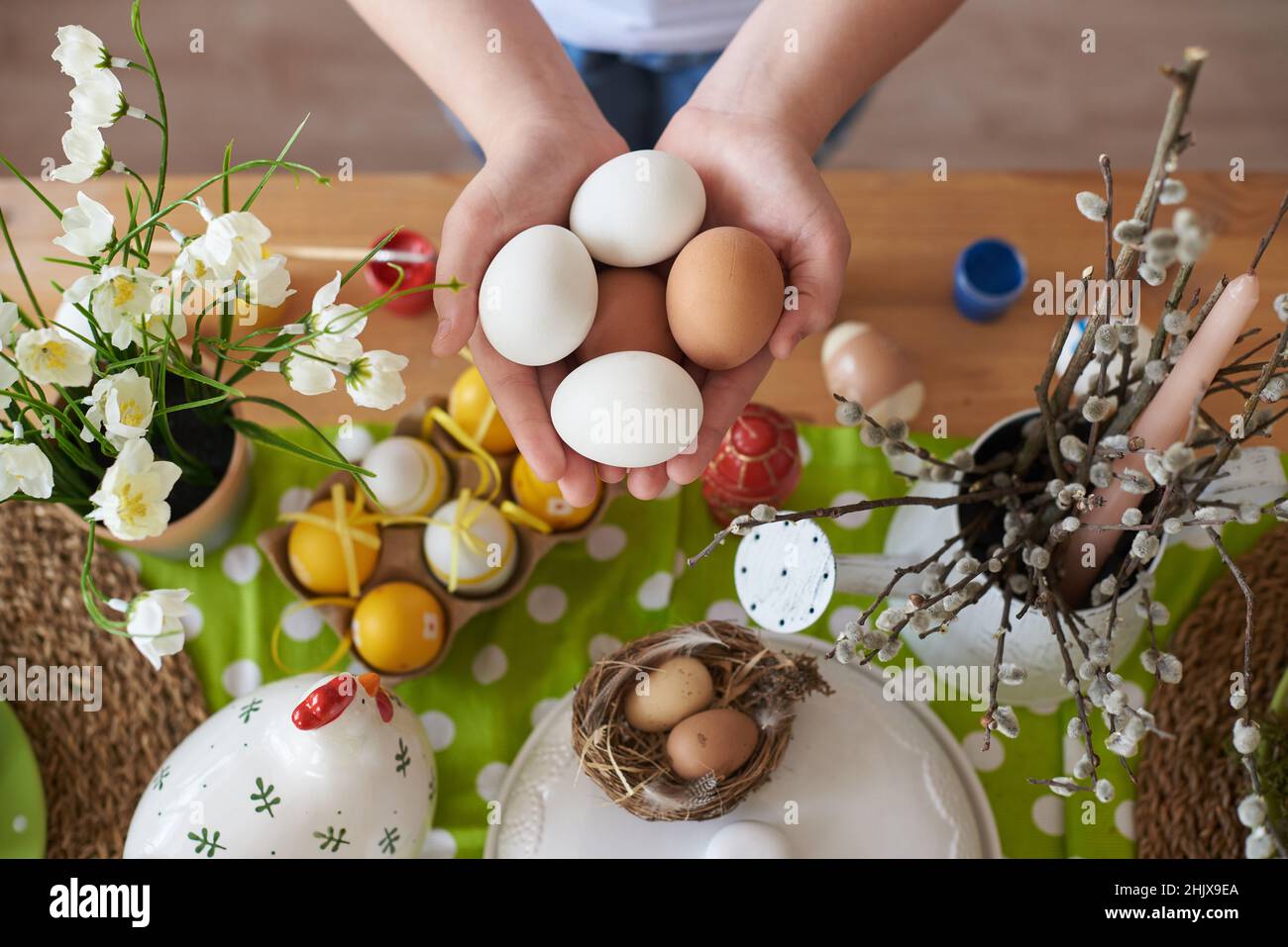 Oeufs dans les mains d'un enfant sur le fond des décorations de Pâques. Banque D'Images