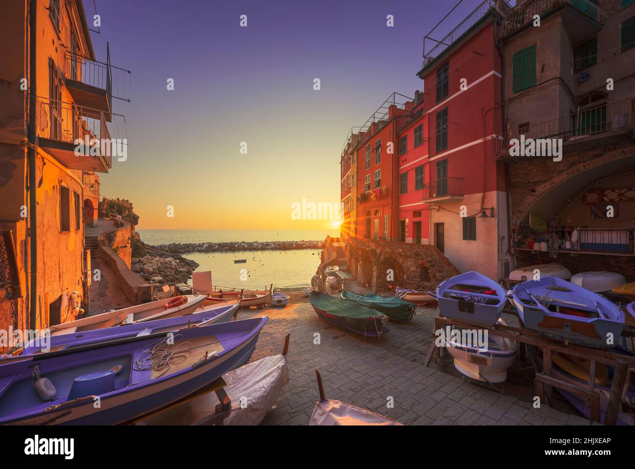 Rue du village de Riomaggiore, bateaux et mer au coucher du soleil, Parc national des Cinque Terre, région de Ligurie, Italie, Europe. Banque D'Images