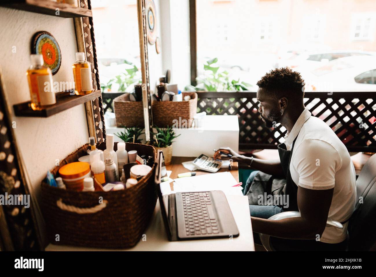 Propriétaire masculin calculant la facture financière à la table dans le salon de coiffure Banque D'Images