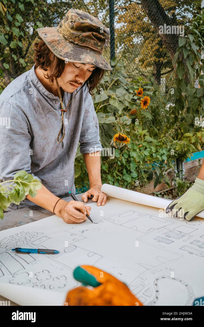 Un écologiste masculin s'appuie sur un plan à table Banque D'Images