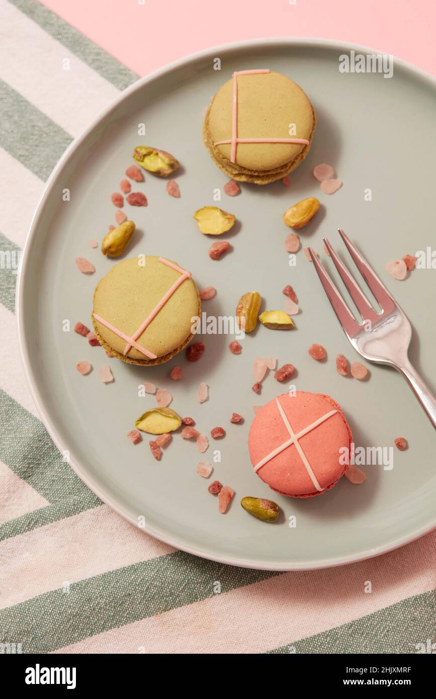 Des macrons colorés sur une assiette verte avec torchon et couverts. Banque D'Images