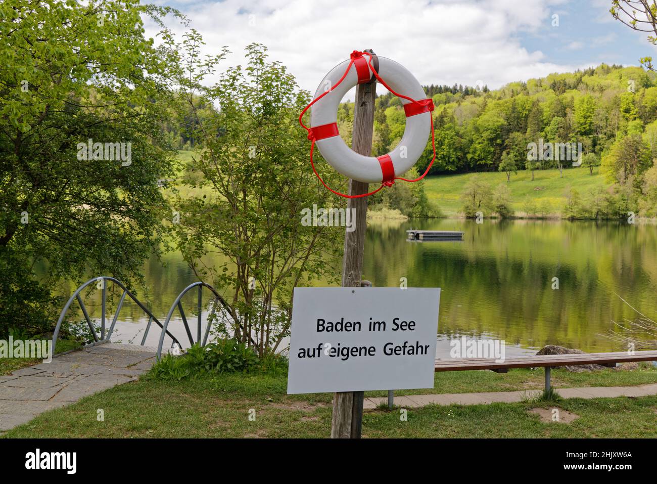 etablissement de baignade avec lac, en premier plan anneau de sauvetage blanc-rouge avec signe d'avertissement texte allemand traduction: nager dans le lac à vos risques et périls Banque D'Images