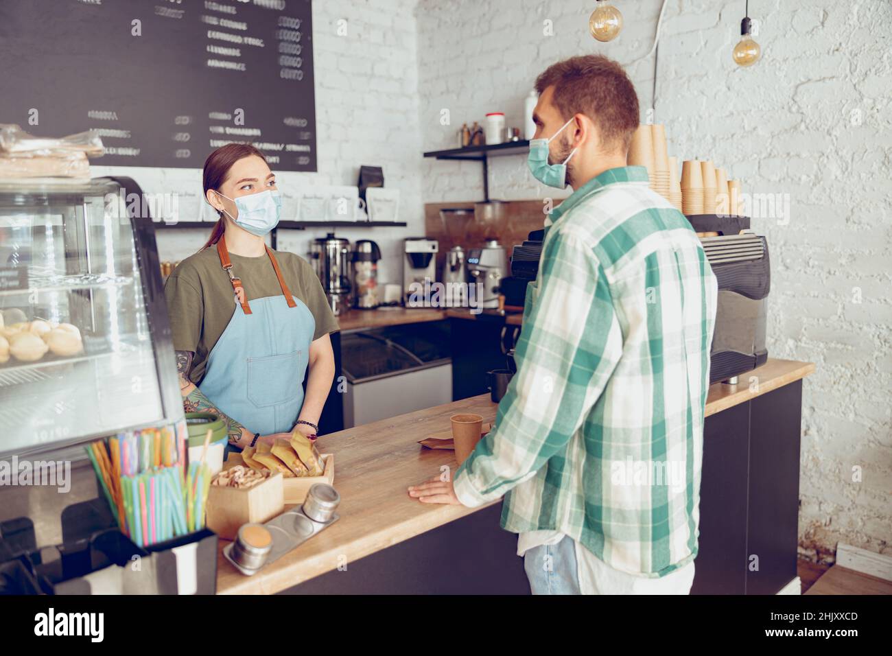 Femme Barista dans un masque médical servant le client dans un café Banque D'Images