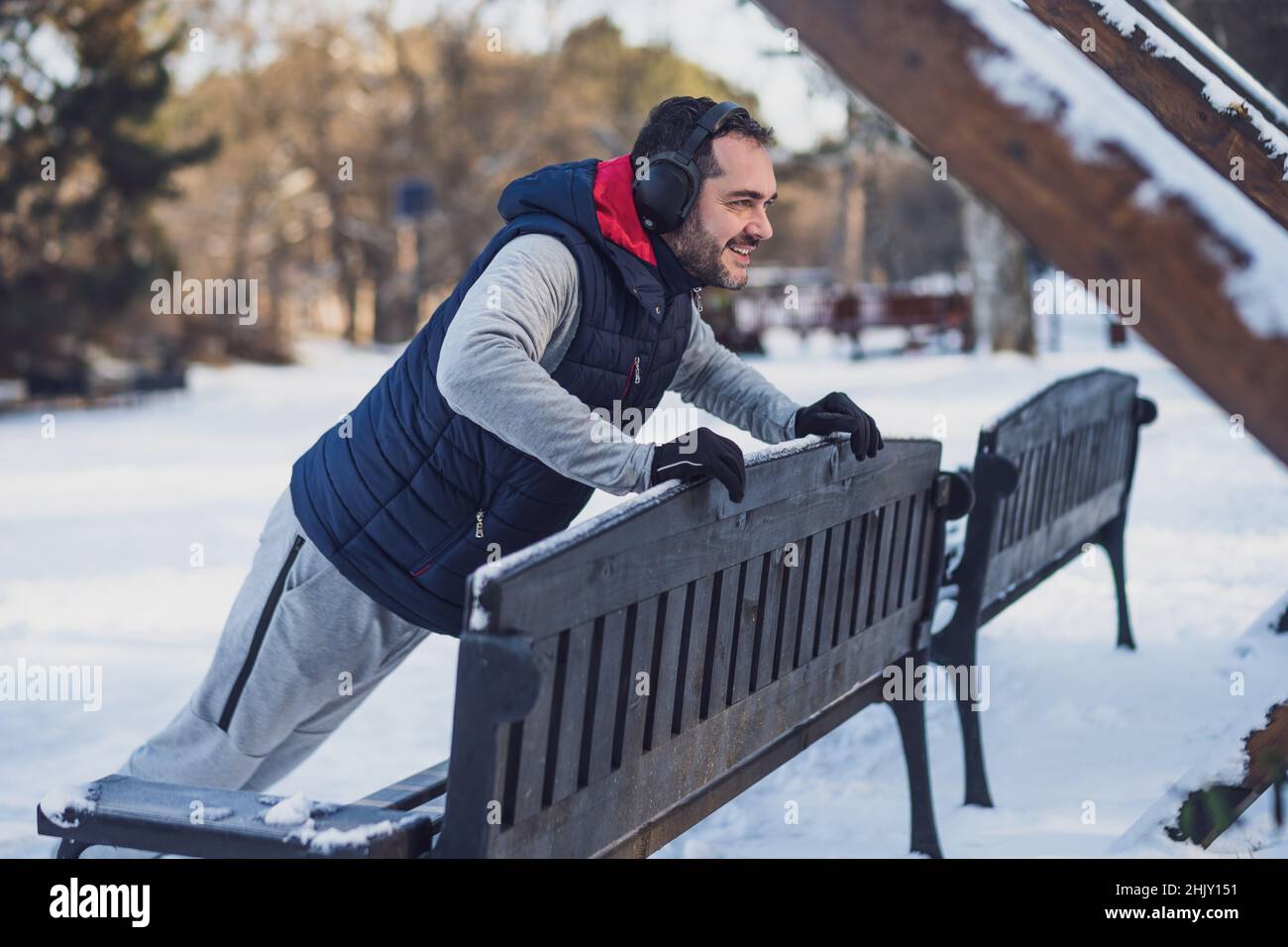 L'homme adulte s'exerce dans le parc en hiver.Il fait des push-ups. Banque D'Images