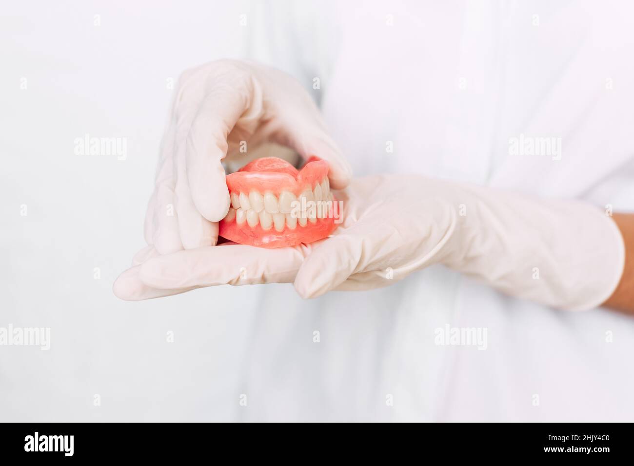 Prothèse dentaire dans les mains du médecin en gros plan.Dentiste tenant un pont dentaire en céramique.Vue avant de la prothèse complète.Pho conceptuel de la dentisterie Banque D'Images