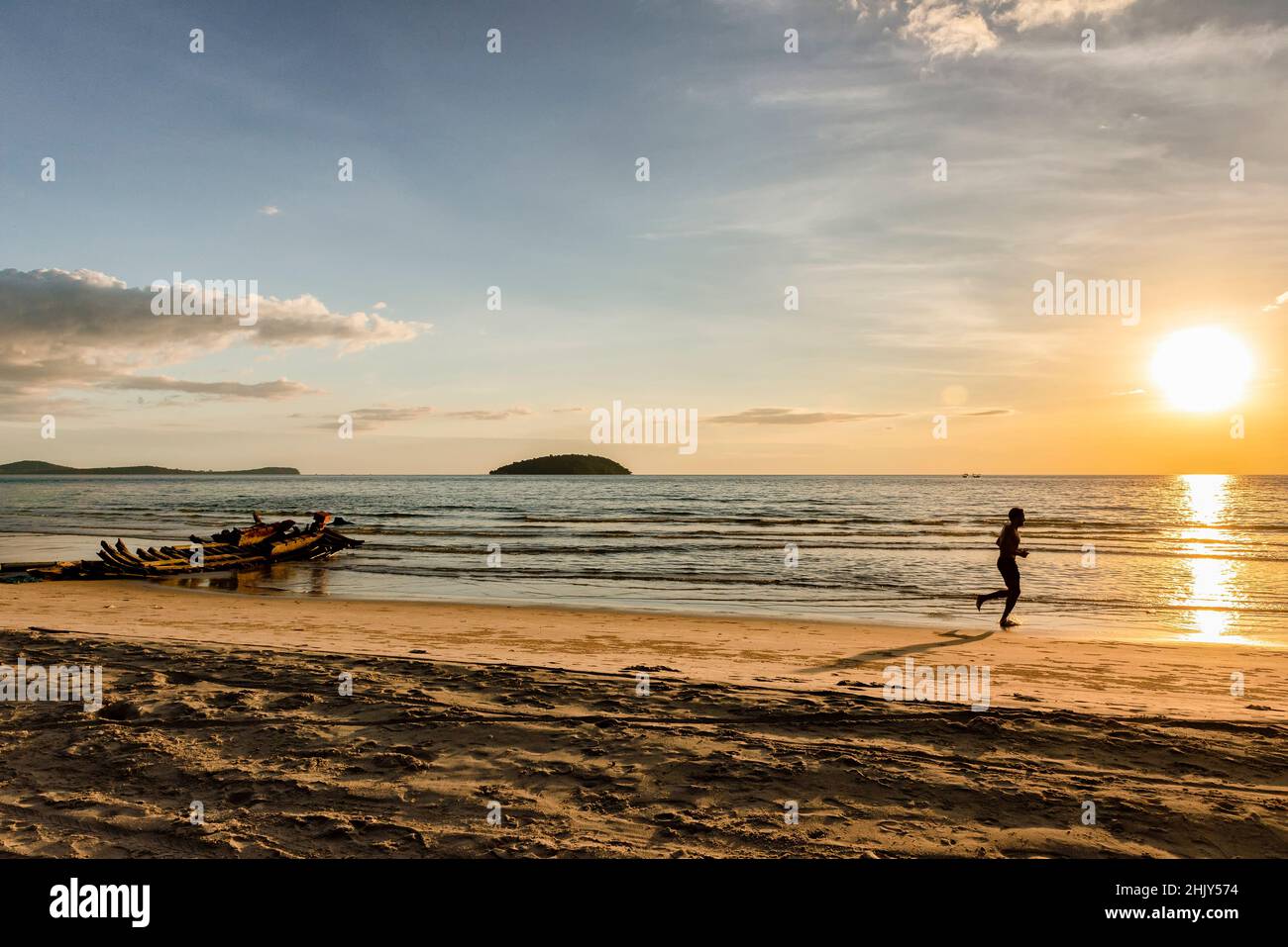 Silhouette d'un homme qui court sur la plage au coucher du soleil Banque D'Images