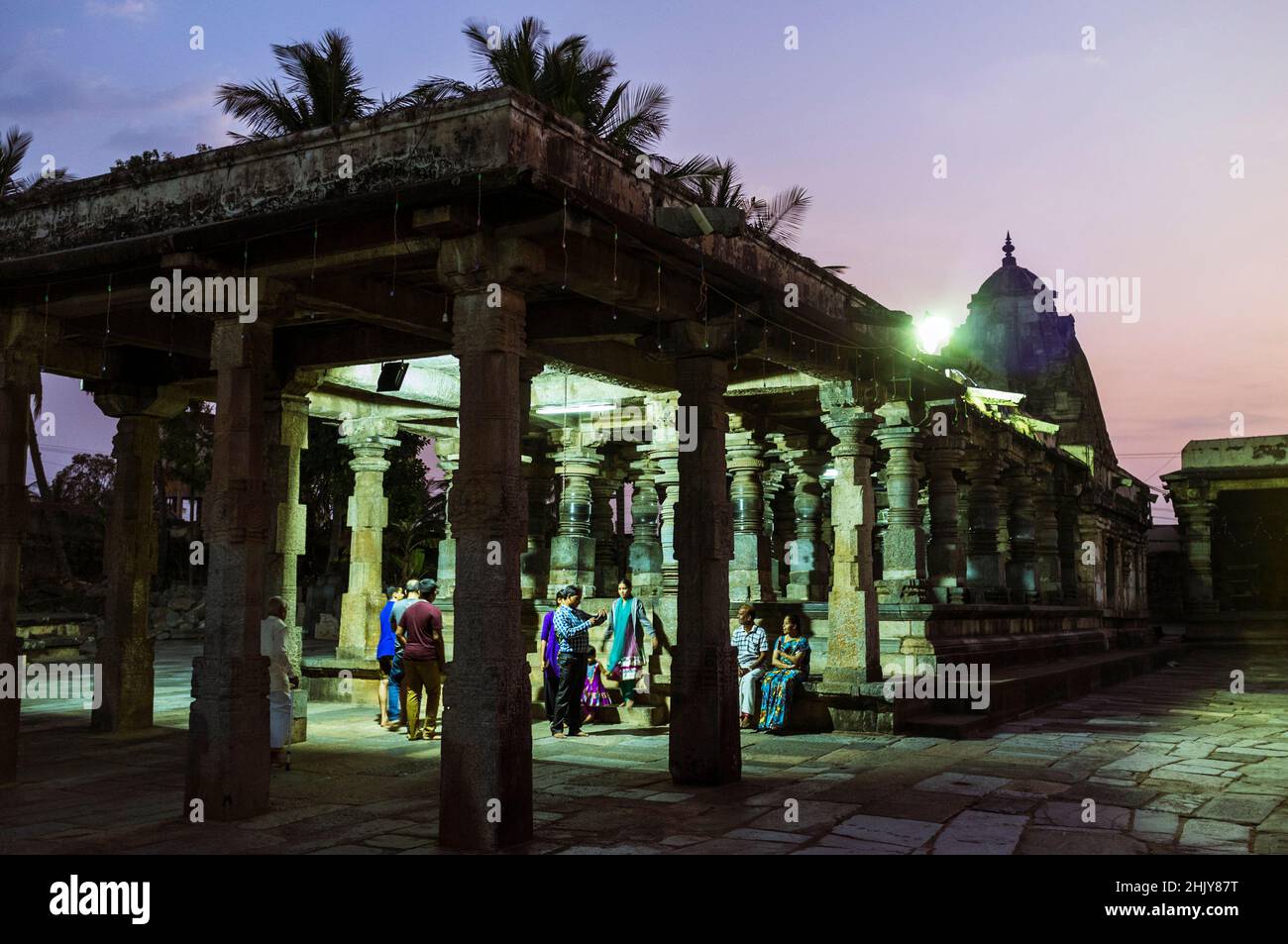 Belur, Karnataka, Inde : Un groupe de personnes se tient au crépuscule sous l'un des temples du complexe du temple de Channakhava. Banque D'Images