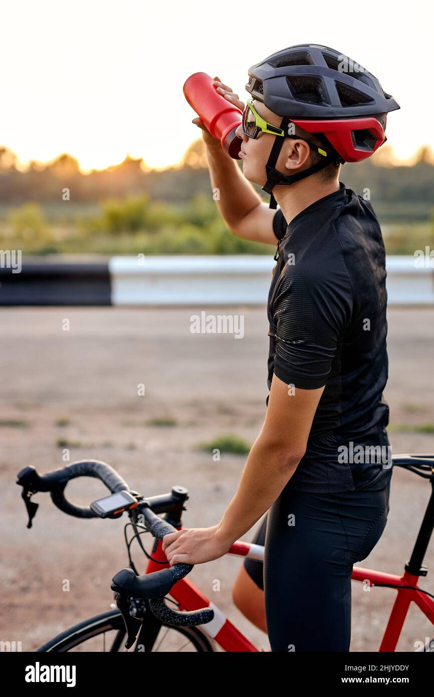 jeune homme caucasien cycliste vêtements de cyclisme et casque prenant la  pause, boire de l'eau après le vélo actif, en tenue sportive. fit athlète g  Photo Stock - Alamy