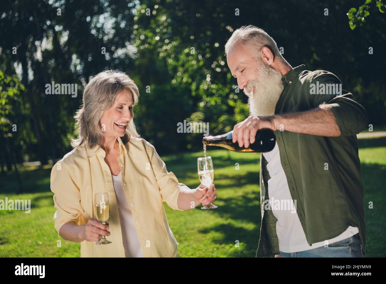 Photo de cool expression Senior White Hair couple boire alcool porter des chemises décontractées à l'extérieur jour de congé dans le parc Banque D'Images
