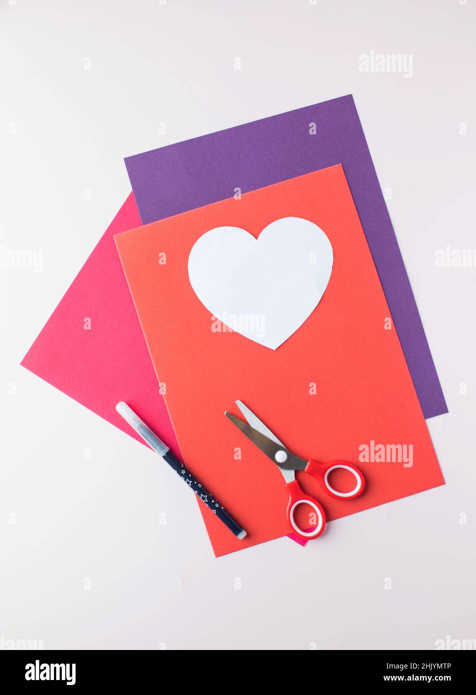 Papier de couleur, ciseaux et un blanc en forme de coeur pour créer une carte cadeau avec vos propres mains. Banque D'Images