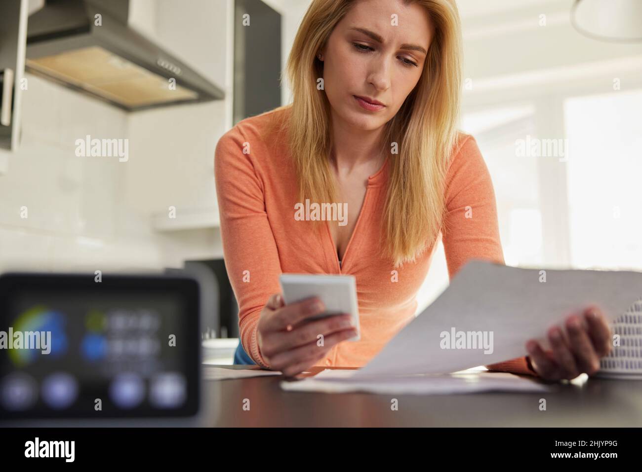 Compteur d'énergie intelligent dans la cuisine mesure de l'électricité et de la consommation de gaz avec la femme regardant des factures avec la calculatrice Banque D'Images